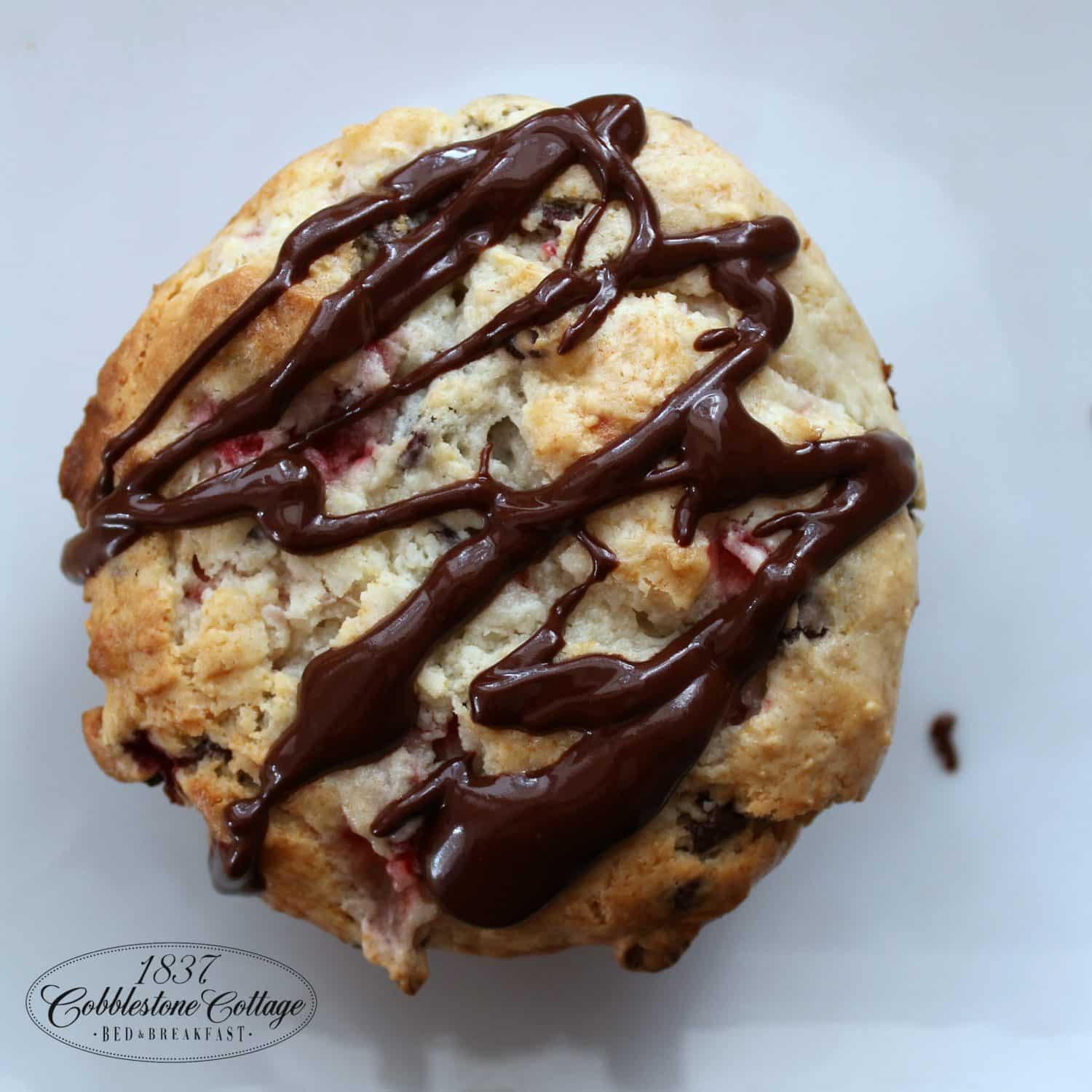 A freshly baked scone drizzled with chocolate sauce.